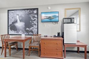 梅德福Travelers Inn Medford I-5的客房设有书桌、冰箱和桌子。