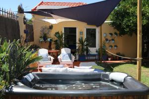 里斯本Geronimo Guest House Belém的庭院内的热水浴池配有椅子和遮阳伞
