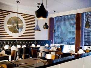 格拉斯哥阿尔托酒店的餐厅设有桌椅和墙上的时钟