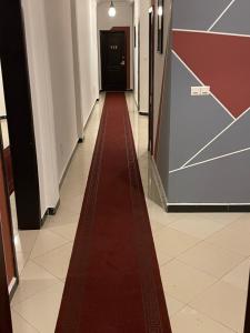 科托努HOTEL LES ARCADES的红地毯在大楼的走廊上走下