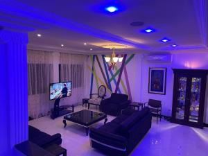 科托努HOTEL LES ARCADES的紫色的客厅配有沙发和电视