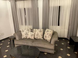科托努HOTEL LES ARCADES的带沙发和玻璃桌的客厅