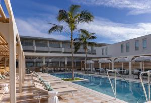 索伦托InterContinental Sorrento Mornington Peninsula的一座带椅子和棕榈树的酒店游泳池
