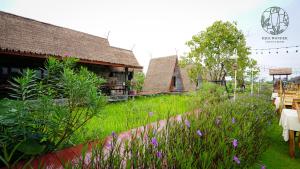 罗勇Rice Wonder Cafe & Eco Resort的一座花园,在一座建筑前种有紫色花卉