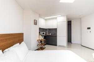 釜山Urbanstay Busan Cityhall的一间带白色床的卧室和一间厨房