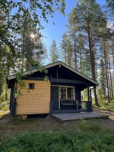 SaariharjuMetsä Kolo的树林中的一个小房子,有门廊