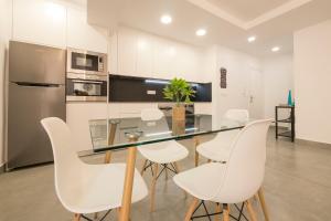 格拉纳达Apartamento Ribera del Genil Centro的厨房配有玻璃桌和白色椅子