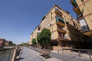 格拉纳达Apartamento Ribera del Genil Centro的前面有长凳的建筑