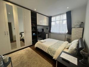 伦敦Deluxe Homestay near Tottenham Hotspur Stadium的一间卧室配有一张床、一张书桌和一面镜子