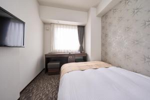 札幌Hotel Axia Inn Sapporo Susukino的一间卧室配有一张床、一个窗口和一张书桌