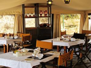 MugumuSerengeti Pioneer Camp的一间设有白色桌椅的用餐室