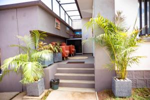 安齐拉贝Yvanka Appart'City Antsirabe的大楼内带楼梯和棕榈树的走廊