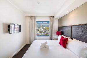 达尔文Suite Escape on the Esplanade with Pool & Balcony的卧室配有带红色枕头的大型白色床
