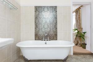基督城The Retreat New Forest, Hinton的浴室设有白色浴缸,配有壁纸