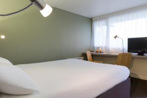梅斯苔丝Kyriad Annecy Nord - Epagny的一间卧室配有一张床、一张书桌和一个窗户。