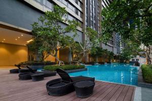 吉隆坡WSD Times 8 Luxury Hotels & Residences的酒店庭院设有游泳池、椅子和树木