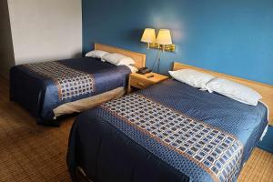 斯托克顿Travelodge by Wyndham Stockton的酒店客房设有两张床和蓝色的墙壁。