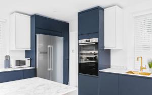 布里斯托Stunning 2 bedroom apartment in fantastic location的厨房配有蓝色橱柜和不锈钢冰箱