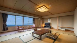 热海热海龟之井酒店别馆(Kamenoi Hotel Atami Annex)的客厅配有桌椅和大窗户