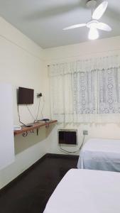 巴乌鲁Falcon Hotel的一间卧室设有一张床、一台电视和一个窗口。