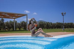 圣塔·马里亚·迪·帕尔玛Villa Barbarina Nature Resort的坐在游泳池旁的比基尼的女人
