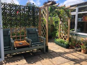 巴恩斯特珀尔Owly 'Ouse的一个带木制凉棚和椅子的花园