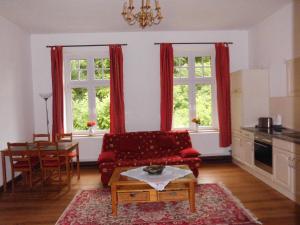 沃伦伯格Gutshaus Wohlenhagen的一间带红色沙发和两扇窗户的客厅