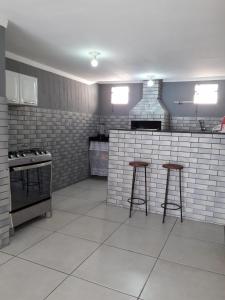 卡波布里奥Casa Super CONFORTÁVEL a 8min da praia do Forte的厨房配有2把酒吧凳和炉灶。