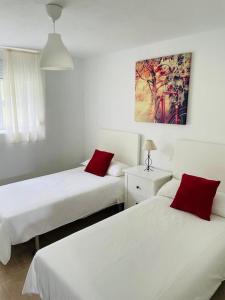 塞埃APARTAMENTO PLAYA DE ESTORDE的客房内的两张床和红色枕头