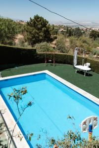 莫纳奇尔Casa rural Balcón de Monachil的一个带桌子和秋千的蓝色游泳池