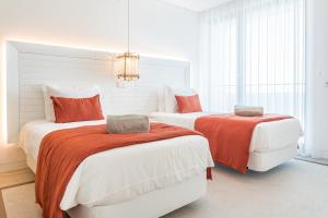 波尔蒂芒Shantivillas Portimão的一间卧室配有两张带橙色和白色床单的床