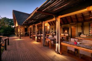 阿马卡拉保护区Bush Lodge – Amakhala Game Reserve的大型木制甲板配有桌子和长凳
