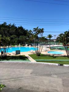 瓜鲁雅Apartamento até 10 pessoas na enseada Guarujá em condomínio clube praia piscinas salão jogos quadra futebol campo parquinho brinquedos Wi-fi Home office的一个带长凳和棕榈树的游泳池