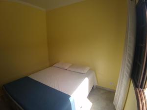MocoócaChalés individuais com piscina a 500M da praia的一间小卧室,卧室的黄色墙壁上配有一张床铺