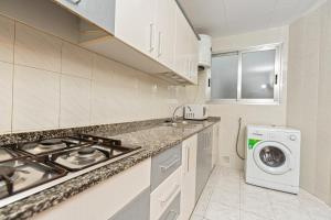贝尼卡洛Apartamentos El Oasis的厨房配有炉灶和洗衣机。
