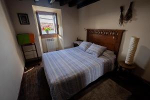 ManurgaMujika Etxea的一间卧室配有一张带条纹床罩的床和窗户