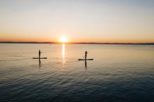 鲍洛通维拉戈什Tópart Hotel的两人在日落时分在水面上划桨