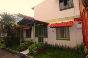 圣何塞F&M Guesthouse的白色的房子,设有绿色的窗户和红色的屋顶