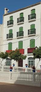 托洛克斯Casa Pepe La Rosa的白色的建筑,设有绿色的窗户和白色的围栏
