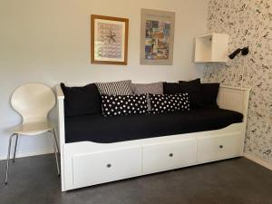 法尔肯贝里Liten ”stuga”的一张带黑色枕头和白色椅子的白色床