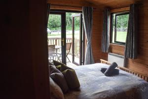 格拉斯哥Lodge at Loch Lomond的一间卧室配有一张床,阳台配有窗户