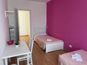 斯特雷萨Villa Vittoria的客房设有两张床、一张桌子和紫色的墙壁