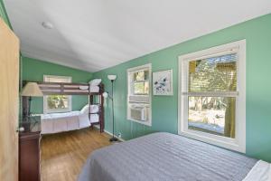 海洋海滩Sea La Vie的一间设有绿色墙壁、一张双层床和两个窗户的卧室