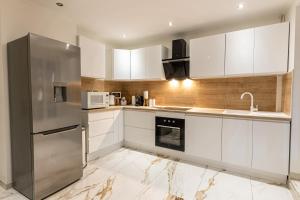 奥尔泽姆Dynasty Home Spa Appartement 100M Jacuzzi Terasse的厨房配有白色橱柜和不锈钢冰箱