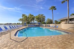 拉斯金Coastal-Zen Ruskin Retreat Less Than 1 Mi to Beach!的一个带蓝色椅子和棕榈树的大型游泳池
