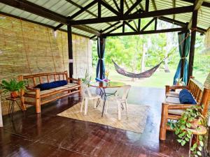 曼巴豪Bahandi Beach Lodge的门廊配有吊床和桌椅