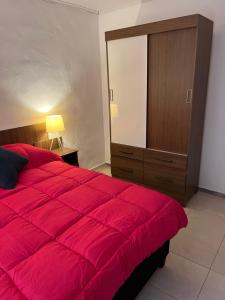 派桑杜Apart Del Este 1的一间卧室配有一张红色大床和一个梳妆台