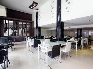 洛坤府MD Grand Hotel Nakhon的一间设有白色桌椅的用餐室