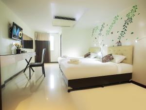洛坤府MD Grand Hotel Nakhon的一间卧室配有一张床和一张桌子及椅子