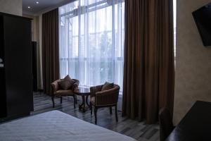 阿斯塔纳Belon Lux Hotel的酒店客房设有带椅子和桌子的窗户。